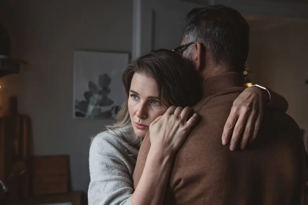 Two people embracing warmly in a cozy, dimly lit room.