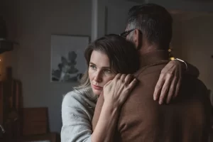 Two people embracing warmly in a cozy, dimly lit room.