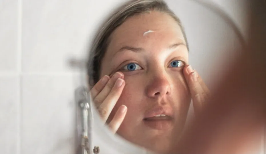 a woman applying cream to her face